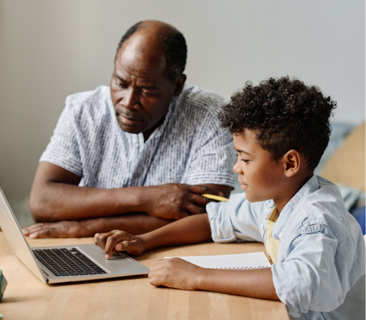 black male tutor with 4th grader boy with a laptop on table