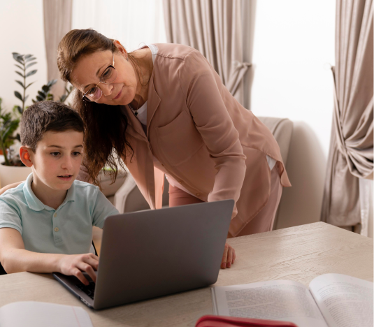 female tutor standing near 6th grader boy looking at laptop on table